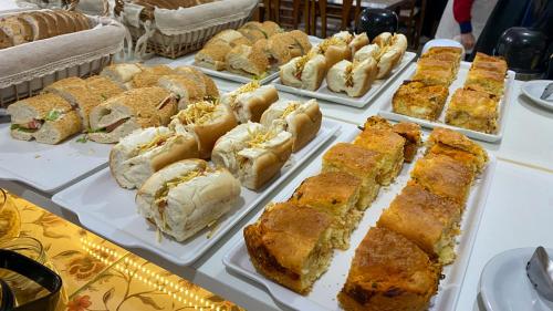 una mesa cubierta con bandejas de sándwiches y bollería en Pousada Vovô Nino, en Gramado