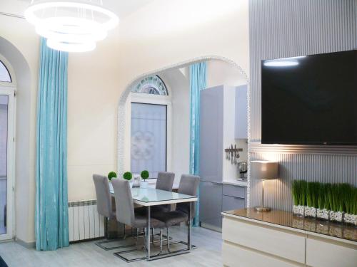 Luxury Centre Located Apartment في كييف: غرفة طعام مع طاولة وتلفزيون بشاشة مسطحة