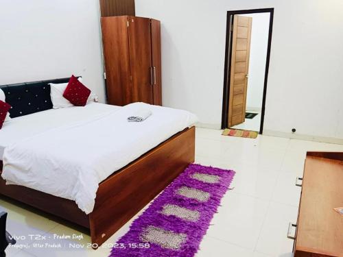 a bedroom with a bed and a purple rug at Mauji's Villa Hotel & Guest House in Prayagraj
