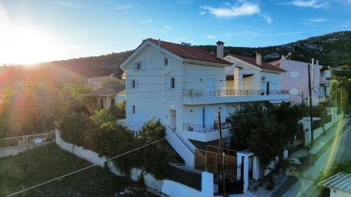 een groot wit huis met de zon erachter bij Beautiful maisonette with a view to the mountains and the sea in Aghia Marina