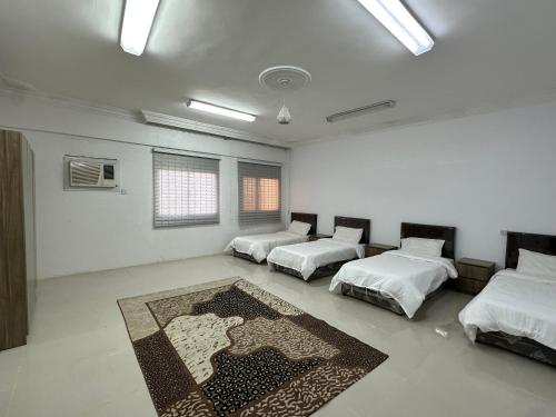 Habitación con 3 camas y alfombra en el suelo en شقق مطله على مسجد قباء, en Medina