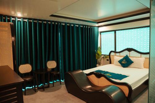 a bedroom with a bed with green curtains and chairs at Sky Hotel in Bắc Giang