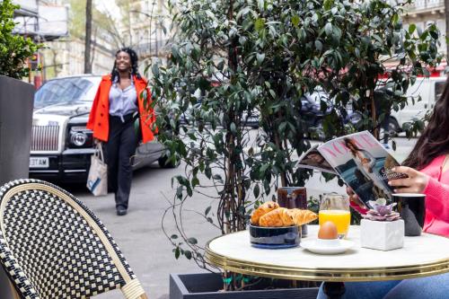 a woman walking down a street with a table with food on it at Lennon by Avalon Hotel Paris Gare du Nord in Paris