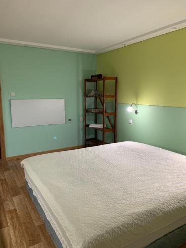 a bedroom with a white bed and a book shelf at Green house Ramuciai in Ramučiai