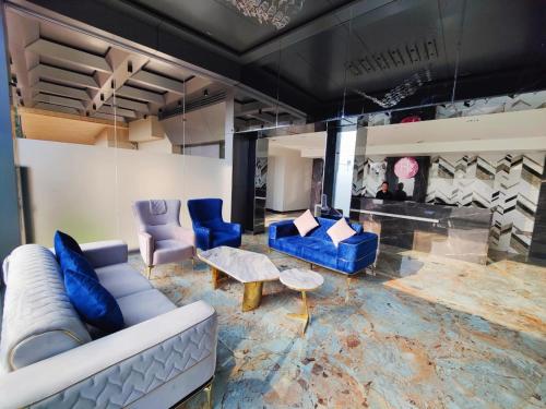 a living room with a couch and blue chairs at Regenta Place Igatpuri in Igatpuri