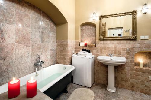 ein Badezimmer mit einer Badewanne, einem Waschbecken und zwei Kerzen in der Unterkunft Apartamenty Kamienica Muzyków Old Town Lublin in Lublin