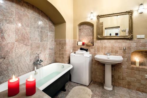 baño con bañera, lavabo y 2 velas en Apartamenty Kamienica Muzyków Old Town Lublin, en Lublin