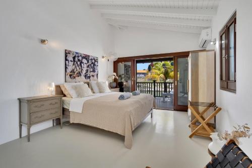 a white bedroom with a bed and a window at Waterlands Villa Sol Bonaire in Kralendijk