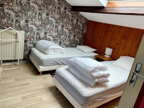 3 camas en una habitación con papel pintado en Chez Madame Titus, en Ormoy-Villers