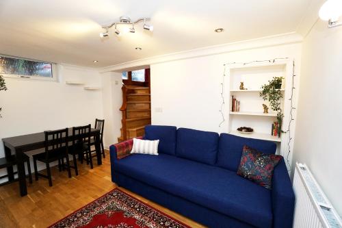 sala de estar con sofá azul y mesa en Cozy Retreat By Aresti Hotels, en Londres