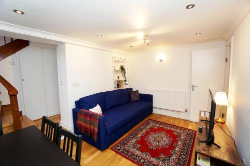 sala de estar con sofá azul y mesa en Cozy Retreat By Aresti Hotels, en Londres