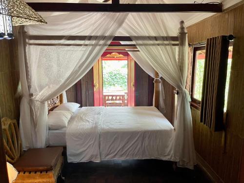 a bedroom with a white canopy bed with a window at The Sangkih Villa Restaurant & Bar in Munduk