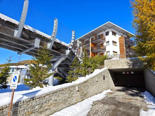 a building behind a brick wall with a tunnel at Hostdomus - Suite Les Etoiles in Sestriere