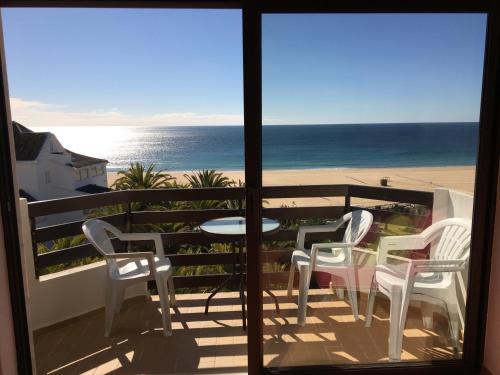 a balcony with chairs and a table and the beach at Appartement, praia da rocha, PORTIMAO in Portimão
