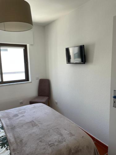a bedroom with a bed and a television on the wall at Appartement, praia da rocha, PORTIMAO in Portimão