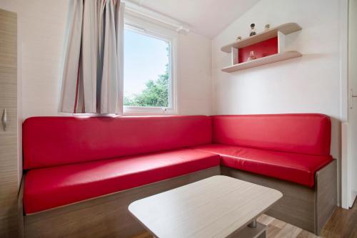 a red couch in a room with a window at Bungalow T2 i i i - 15 Min Nazaré in Pataias