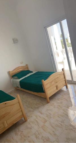 a bedroom with two beds and a large window at Dar el benet in Djerba
