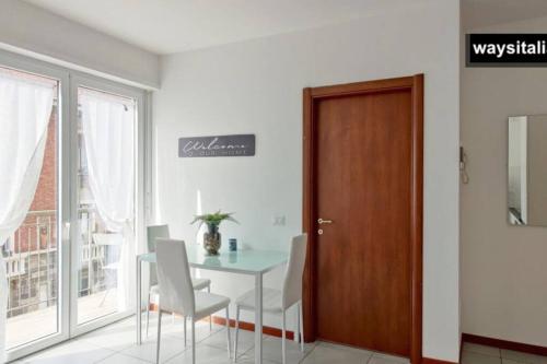 Certosa District Apartment في ميلانو: غرفة طعام مع طاولة وكراسي وباب
