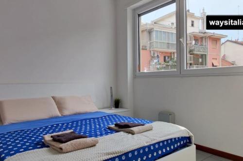Certosa District Apartment في ميلانو: غرفة نوم بسرير مع نافذة ومنشفتين