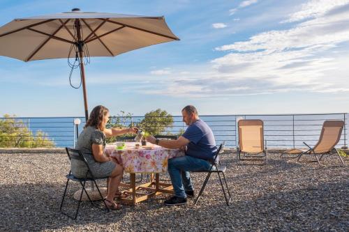 a man and woman sitting at a table under an umbrella at casa Ciapin in Cipressa