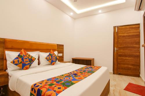 a bedroom with a large bed with colorful pillows at FabHotel Ambassador in Chandīgarh