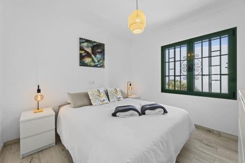 a white bedroom with a white bed and a window at Jardin del sol 17 in Playa Blanca