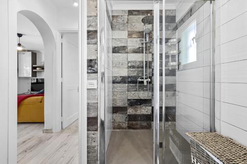 a glass shower in a bathroom with a brick wall at Jardin del sol 17 in Playa Blanca
