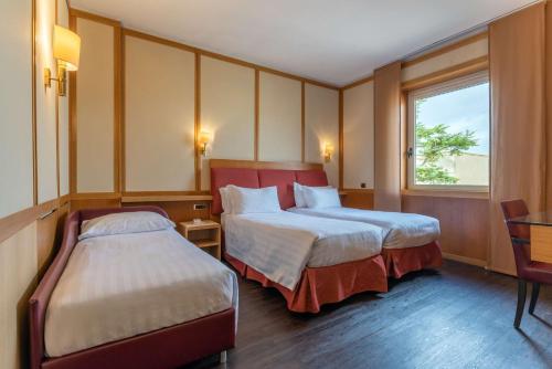 a hotel room with two beds and a window at Best Western Hotel President - Colosseo in Rome