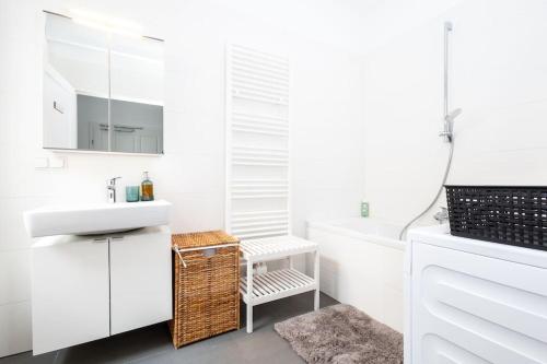 ein Badezimmer mit weißen Schränken, einem Waschbecken und einer Badewanne in der Unterkunft OrestaLiving - 2BR On the Danube Canal in Wien