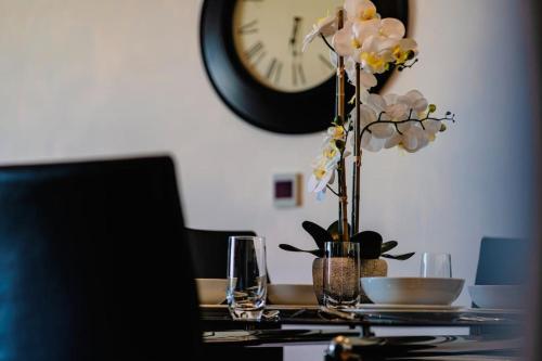 a table with a vase of flowers and a clock at Marina with a view / 2 bd flat in Brighton & Hove