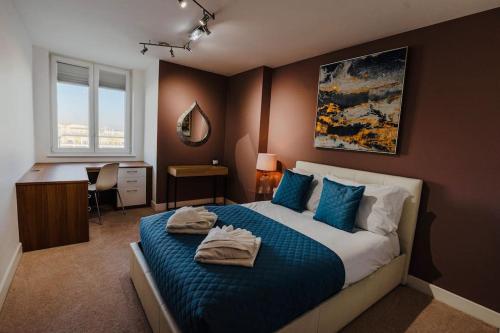 a bedroom with a bed with blue sheets and a desk at Marina with a view / 2 bd flat in Brighton & Hove