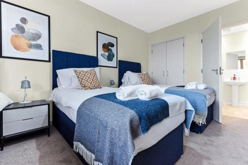 ミルトン・キーンズにあるCity Penthouse with Scenic View Balconyのベッドルーム1室(青と白のシーツが備わるベッド2台付)