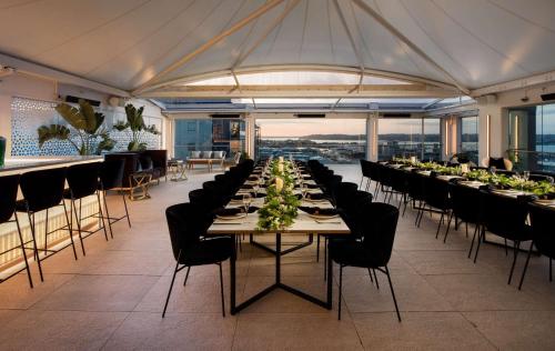 un comedor con una mesa larga con sillas negras en Rydges Auckland en Auckland