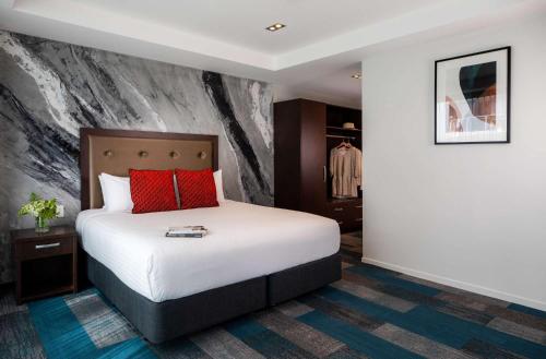 a hotel room with a bed with red pillows at Rydges Auckland in Auckland