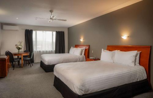 a hotel room with two beds and a desk at Arawa Park Hotel, Independent Collection by EVT in Rotorua