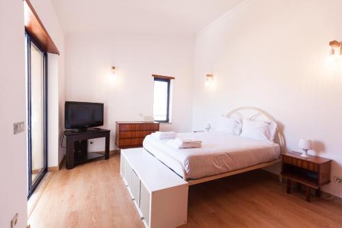 une chambre blanche avec un lit et une télévision dans l'établissement FLH Caparica Town House with Pool, à Costa da Caparica
