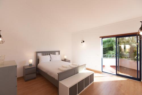 a white bedroom with a bed and a large window at FLH Caparica Town House with Pool in Costa da Caparica