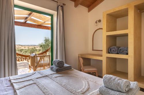 ein Schlafzimmer mit einem Bett und einem großen Fenster in der Unterkunft Monte Flora Farmhouse in Sardoa