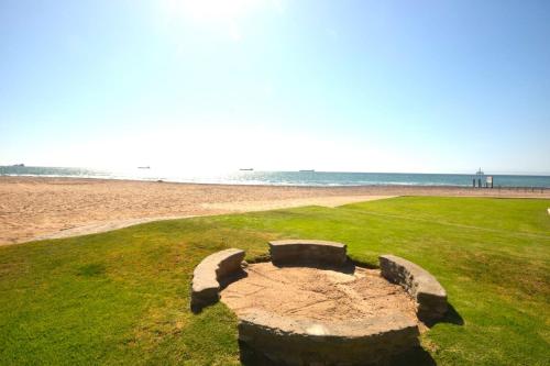 スワコプムントにあるOcean Dream Self-Cateringの浜辺の芝生に座る石のベンチ