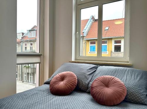 two red pillows on a bed in front of a window at Samurai Room in Gdańsk