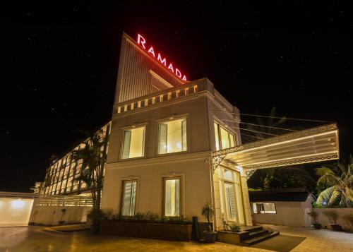 a white building with a red neon sign on it at Ramada by Wyndham Goa Arpora in Arpora