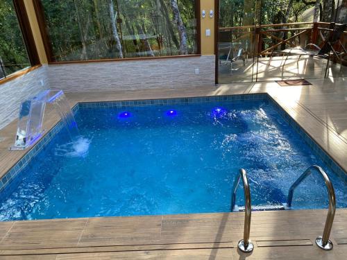 a swimming pool with blue lights in a house at Chalés Recanto das Montanhas in Monte Verde