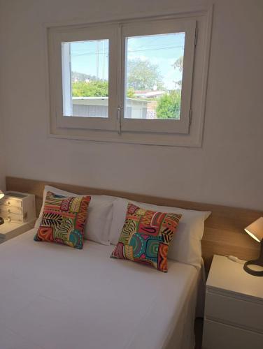 a bed with two pillows sitting under a window at Villa Franz House Casa de Invitados in Canyelles