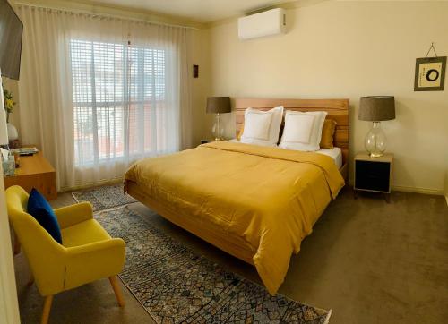 a bedroom with a large bed and a yellow chair at Luxury Inner City Townhouse in Bendigo