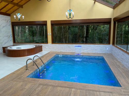 a large swimming pool in a room with a tub and a bath tub at Chalés Recanto das Montanhas in Monte Verde