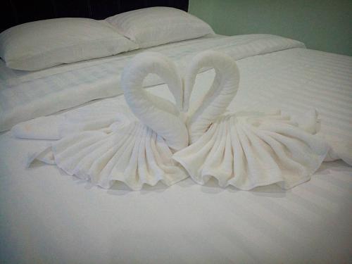 dois cisnes feitos de toalhas numa cama em การ์เด้นวิว รีสอร์ท em Trang