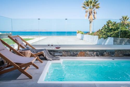 a swimming pool with two chairs and a table at Niriides Palace in Gournes