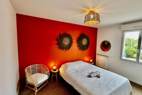 a bedroom with a red wall with a bed and a chair at Maison Style & Espace à Angers in Angers