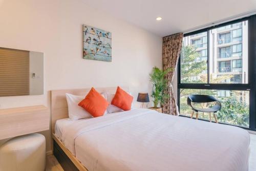 チェンマイにあるModern Condo in Nimman (F309) by Pimolplaceのオレンジ色の枕と窓のあるベッドのある寝室