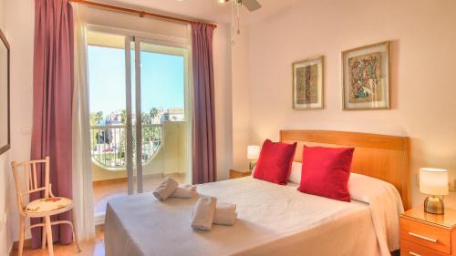 デニアにあるResidencial Playa Sol IIIのベッドルーム1室(赤い枕のベッド1台、窓付)